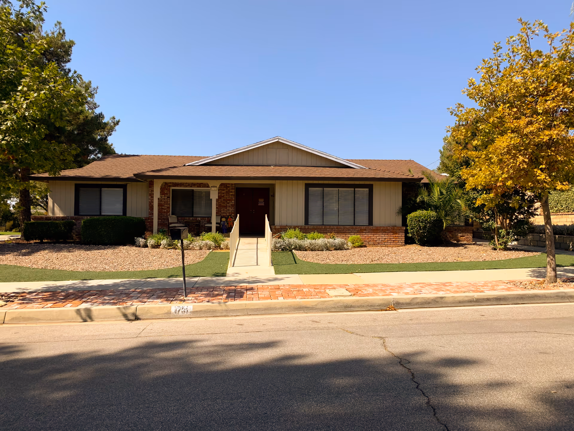 Single-story ranch-style building with a central ramped entrance, brick accents, and a landscaped front yard under a clear sky.