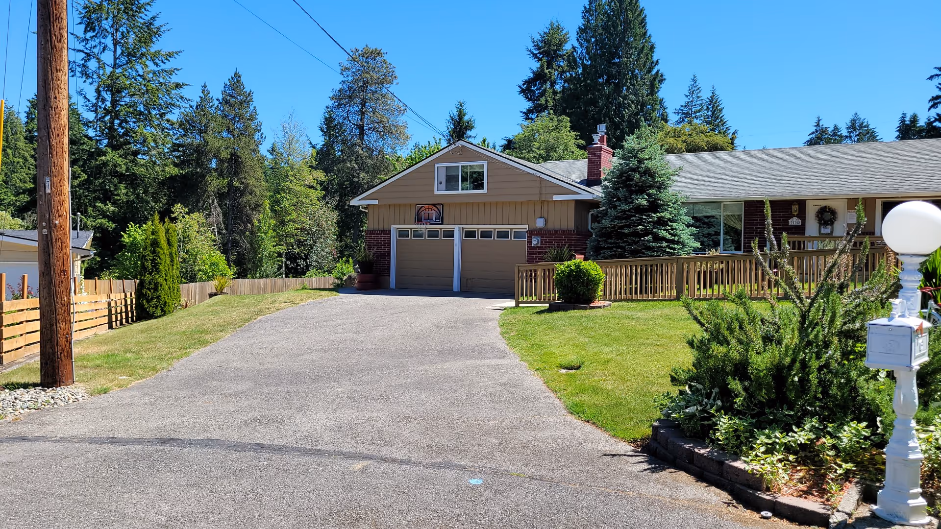 Single-story facility with a long driveway, garage, wooden fence, and manicured front yard.