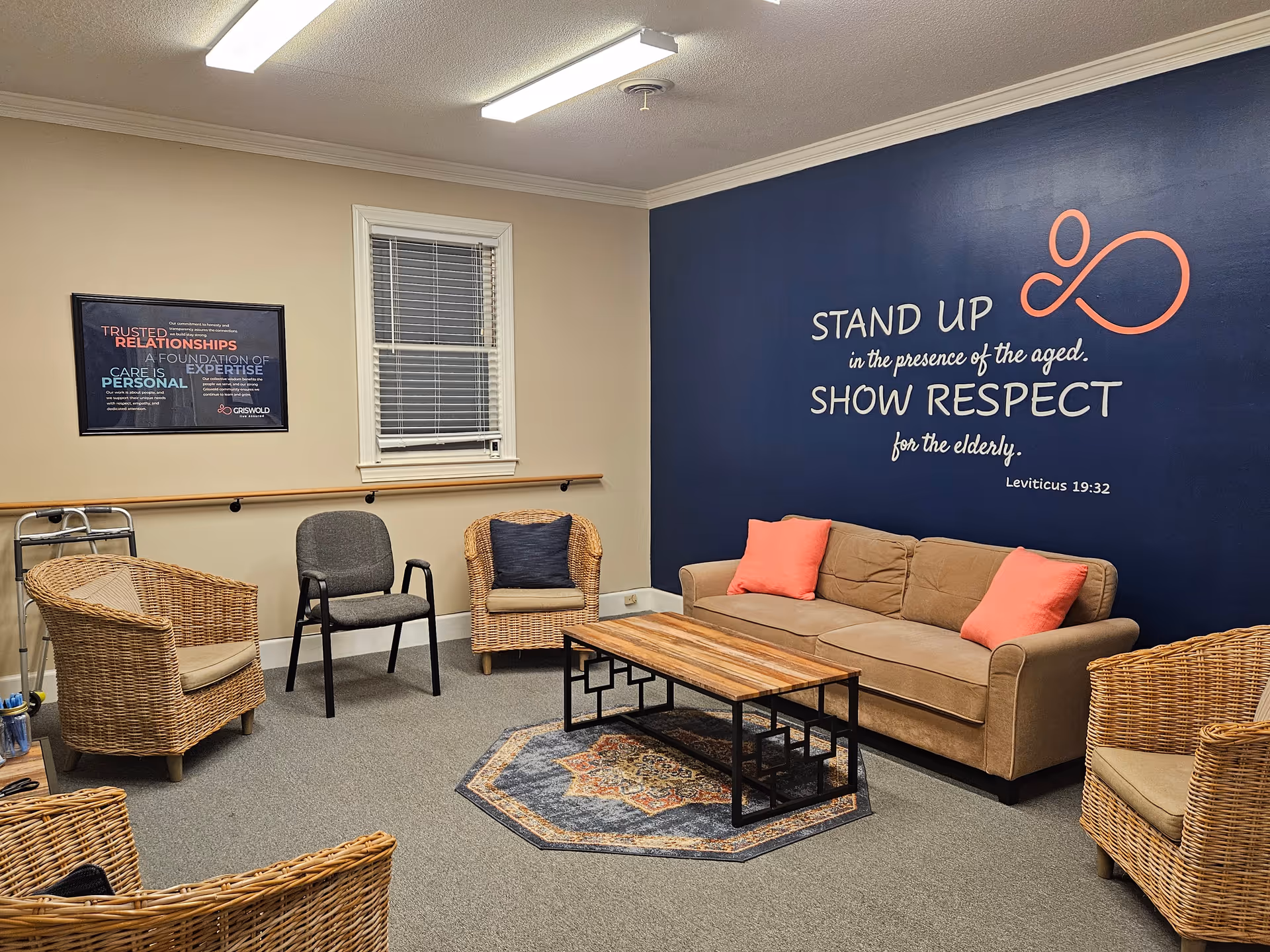 A cozy lounge area with wicker chairs, a sofa, coffee table, and blue wall mural.