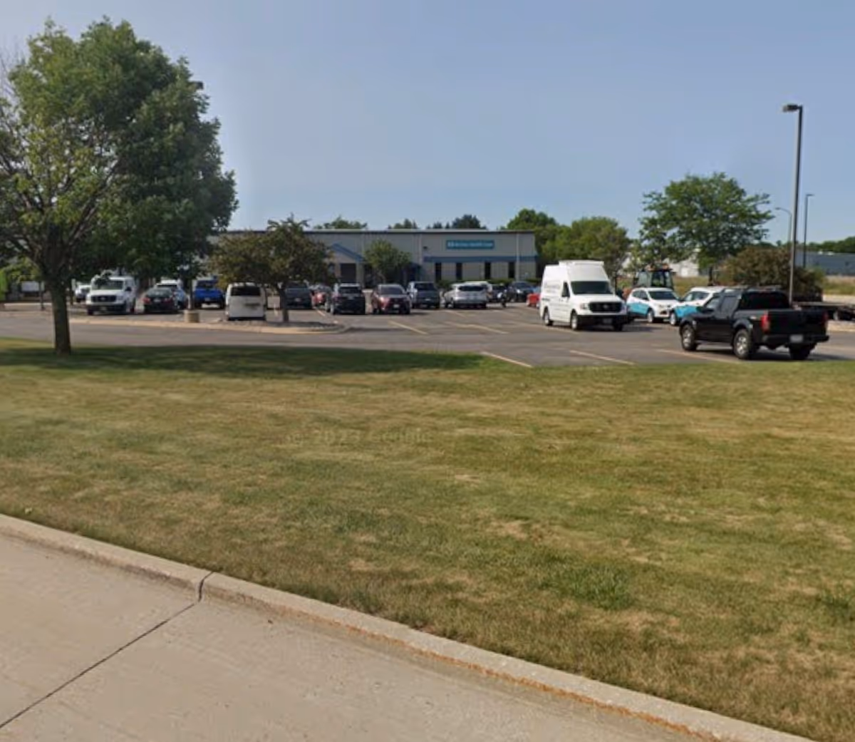Parking lot in front of Aurora Visiting Nurse Associates building with multiple parked cars.