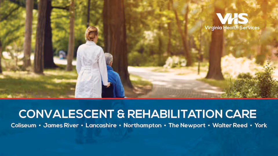 A healthcare professional in a white coat pushing an elderly person in a wheelchair along a tree-lined path in a park or garden setting during daytime.