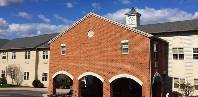 Exterior view of Seaton Springwood senior living facility featuring brick arches and a clock tower.