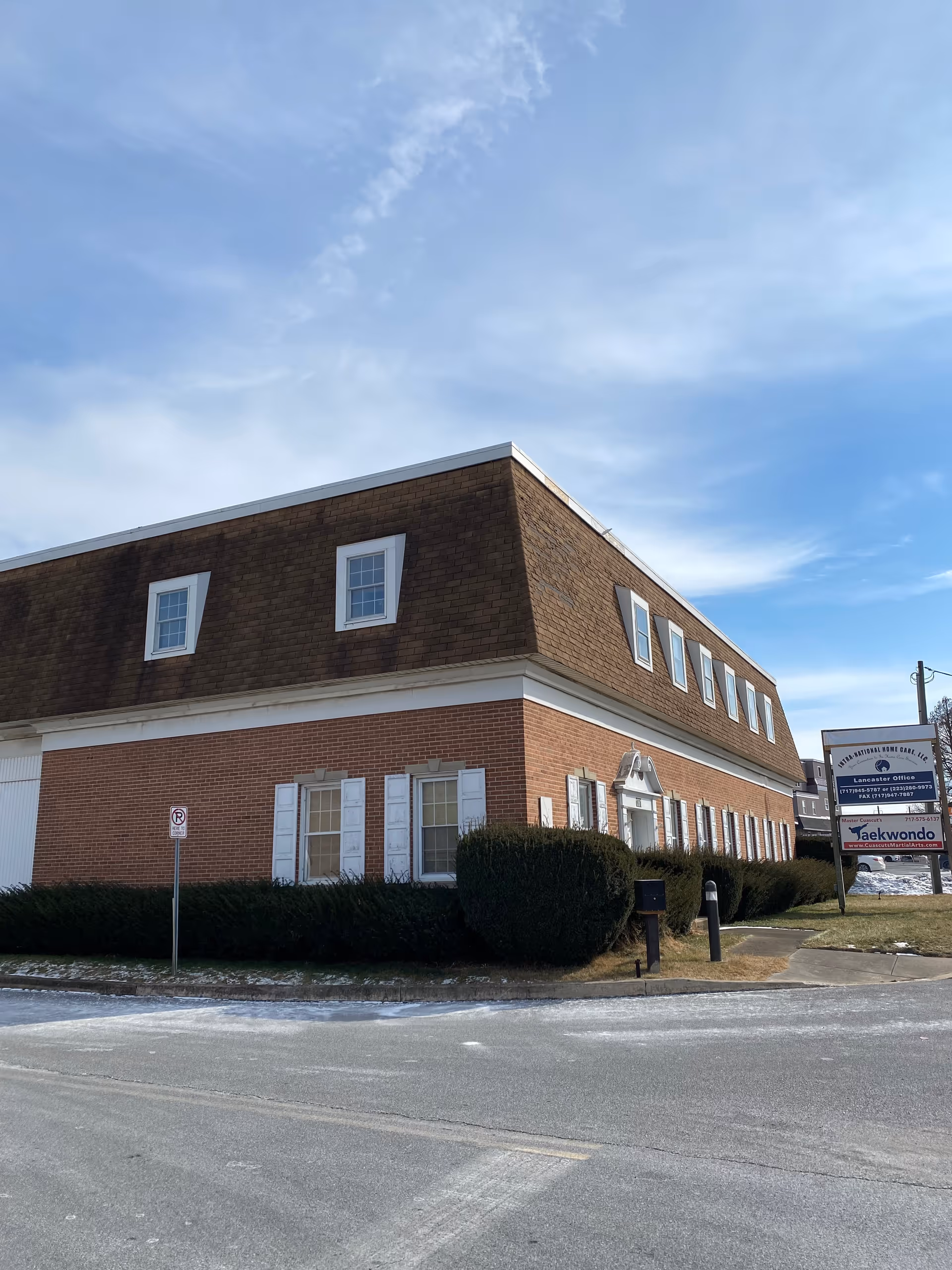 Exterior of INTRA-NATIONAL HOME CARE, LLC facility, brick building with brown sloped roof and white-framed windows.