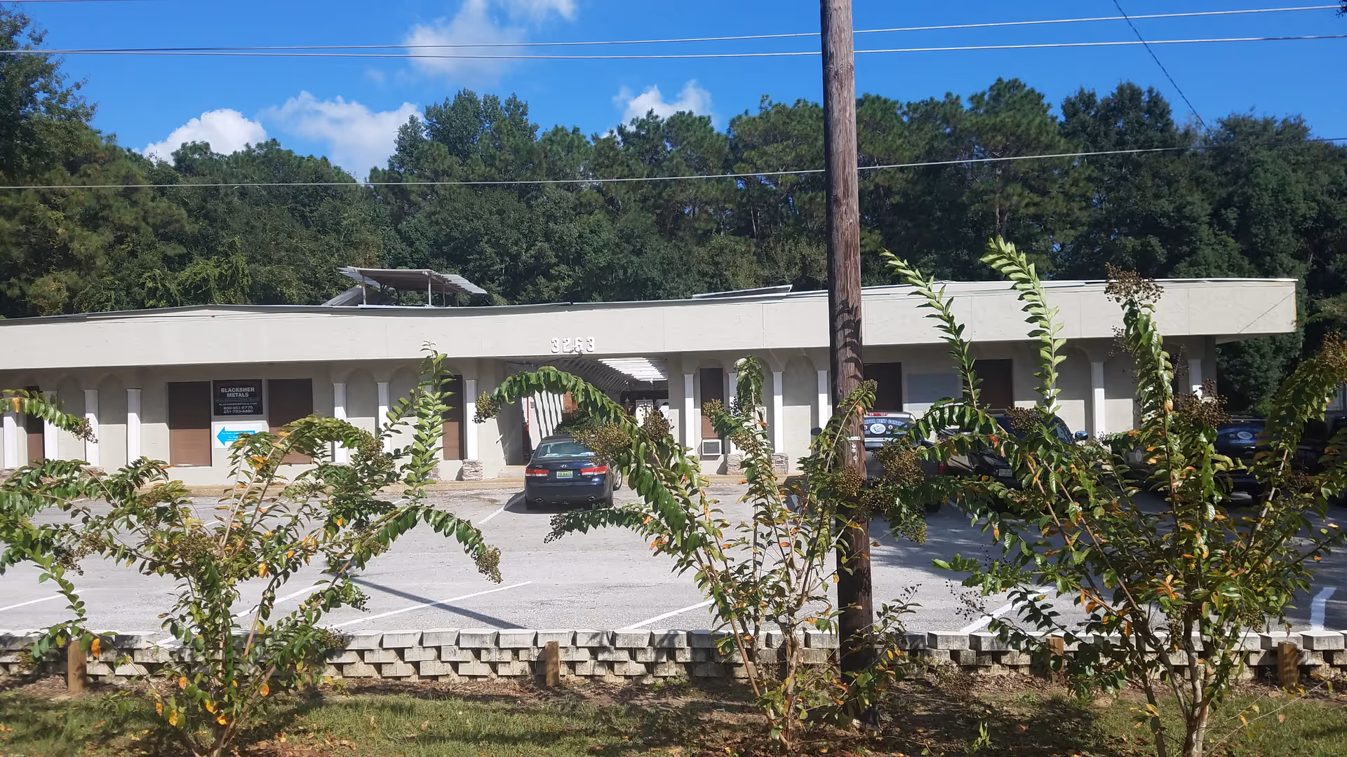 Exterior view of a single-story senior care facility with parking and trees in front.