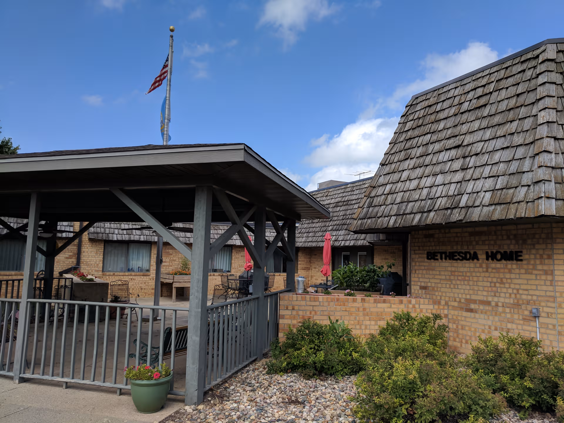 Exterior view of Bethesda Home with a covered outdoor seating area and flag.