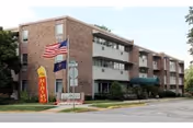 Three-story brick retirement building with American flag and street signage.