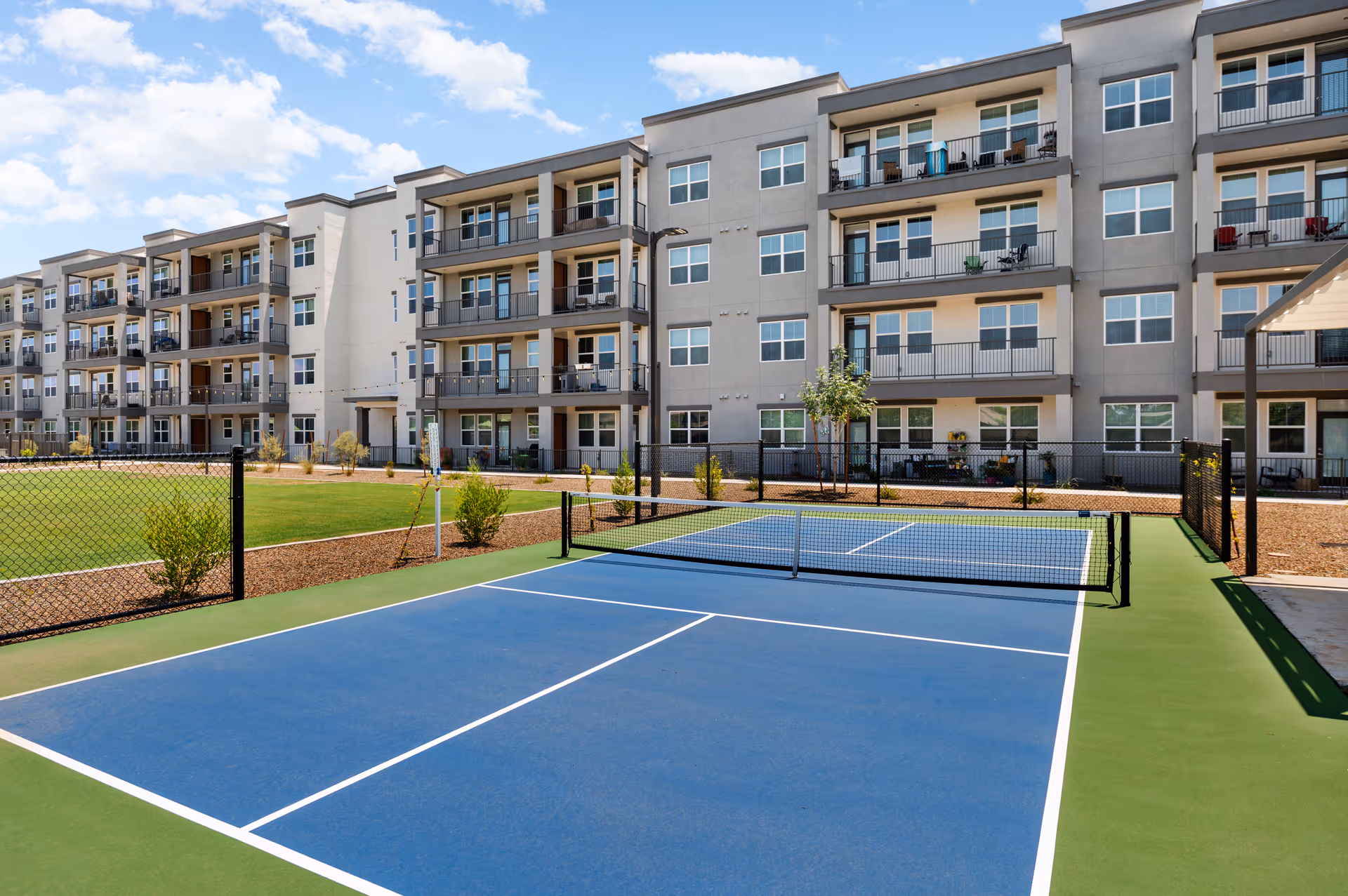 Exterior view of Amberlin Arrowhead with a blue outdoor tennis court in front