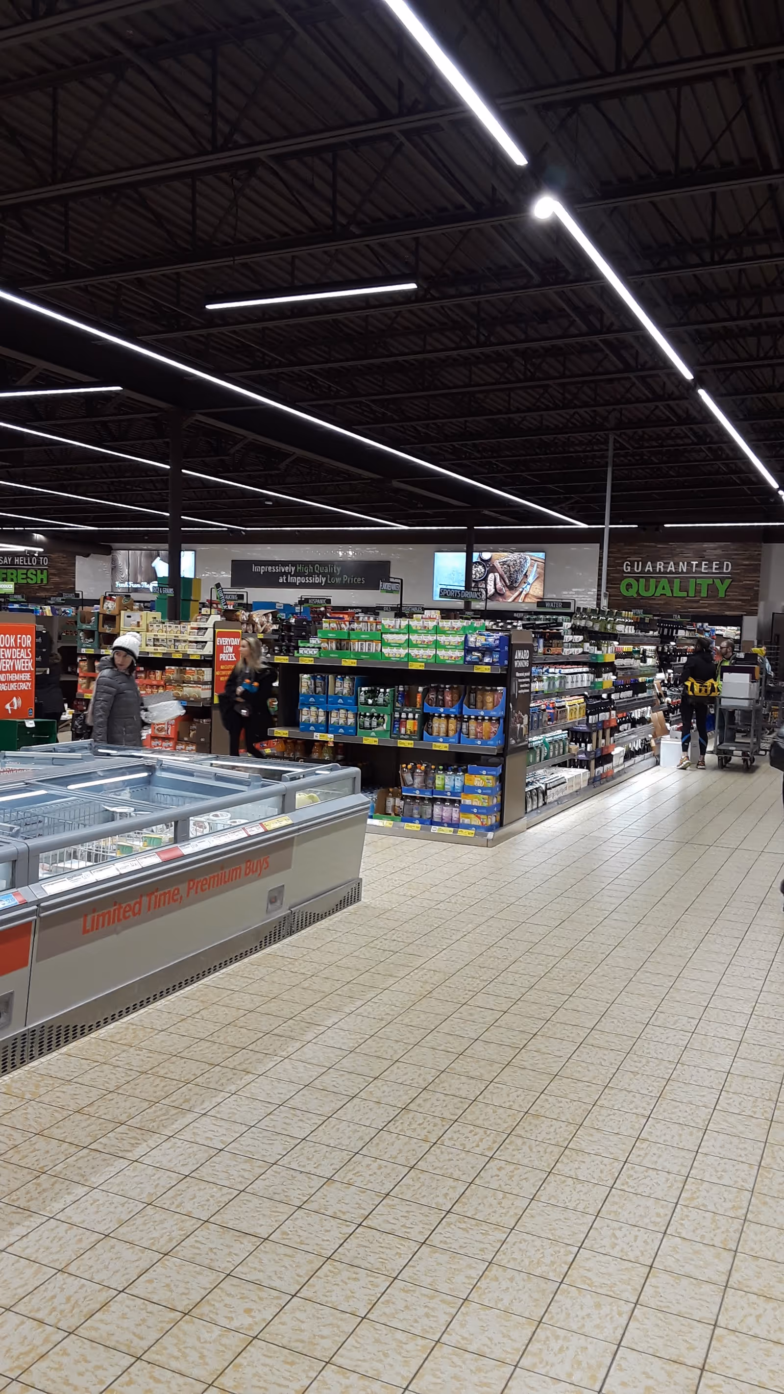 Grocery store interior with aisles, freezers, and shoppers walking through