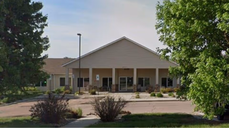 Front exterior of Cayman Court Assisted Living Facility with parking and trees