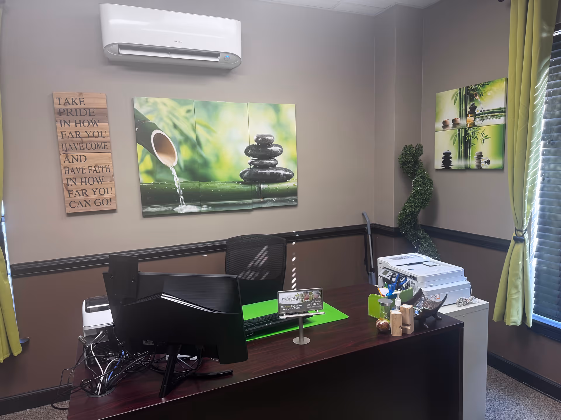 Office workspace with dual monitors, printer, and wall art.