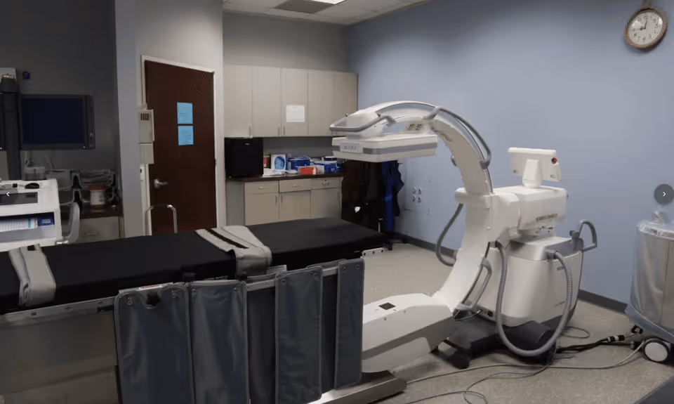 Hospital-style procedure room with a large imaging device and an examination table