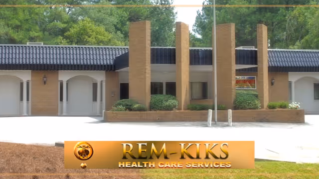 Front view of a brick healthcare facility with tall columns and a gold Rem-Kiks sign.