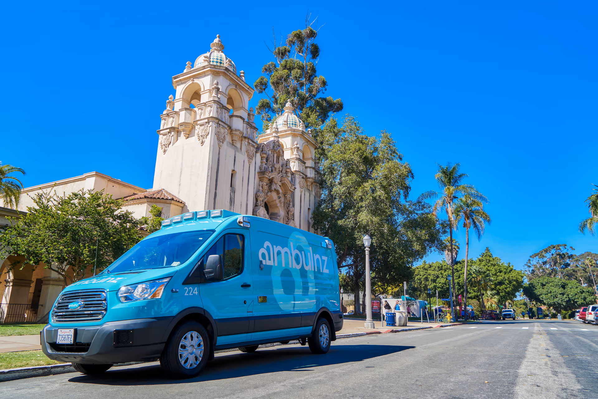 blue ambulnz van parked on a street in front of an ornate building facade