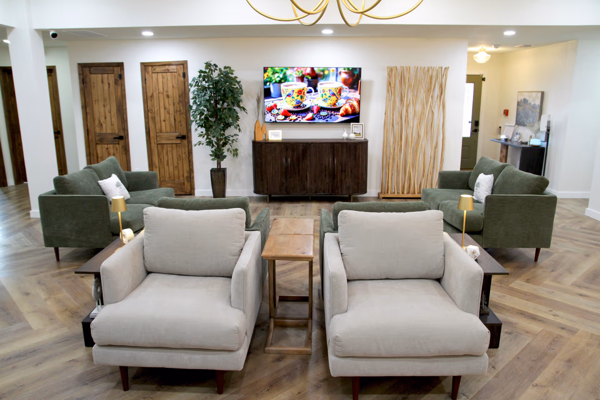 A modern furnished lounge in a senior living facility with sofas, chairs, and a TV.