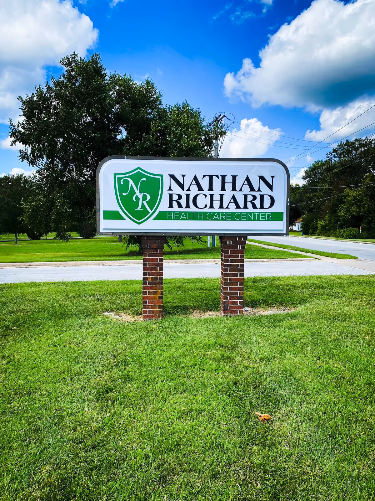 Outdoor sign for Nathan Richard Health Care Center on a grassy lawn with trees
