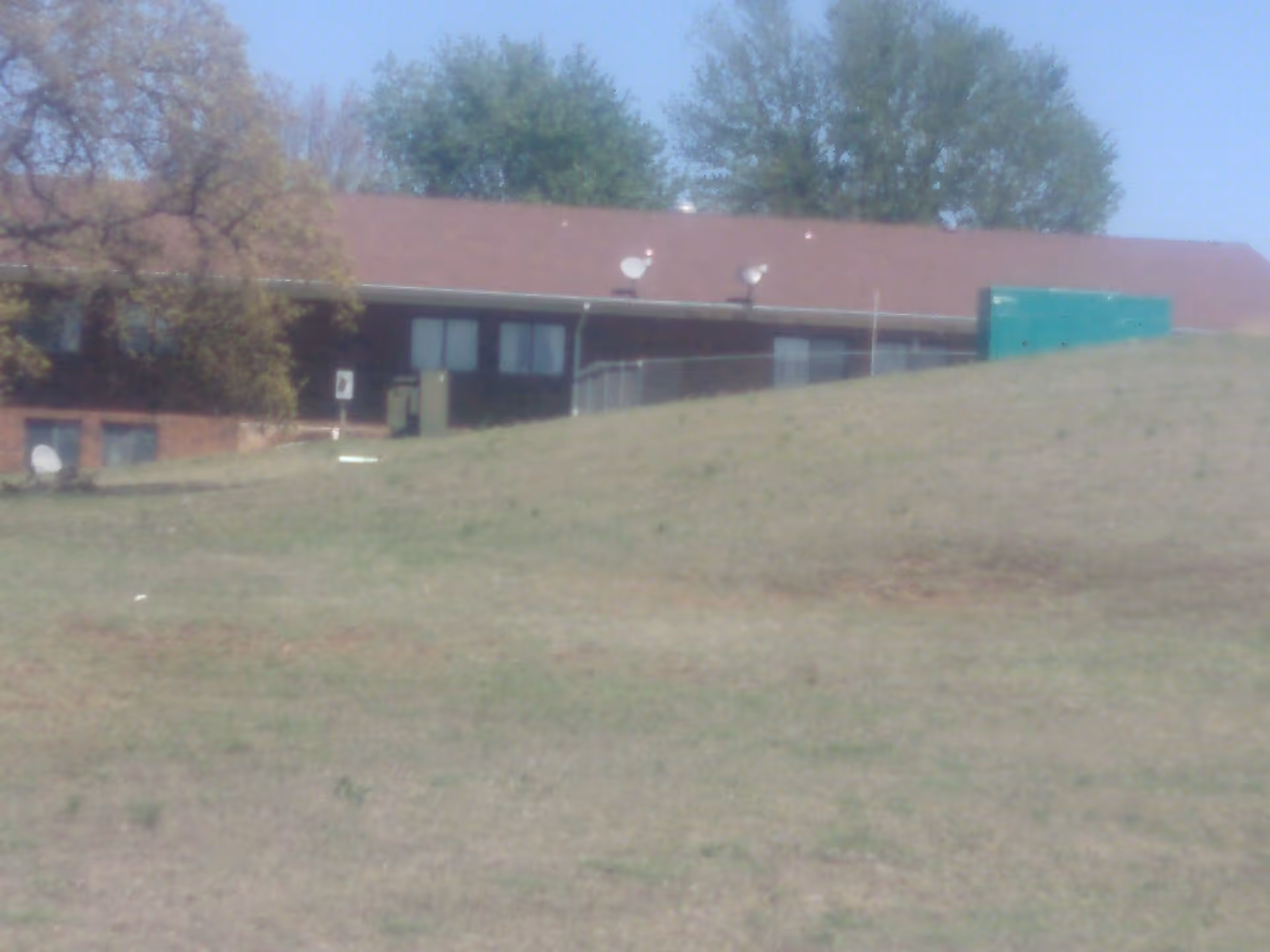 Front exterior of The Wolfe Living Center at Summit Ridge, a single-story building with grassy hill.