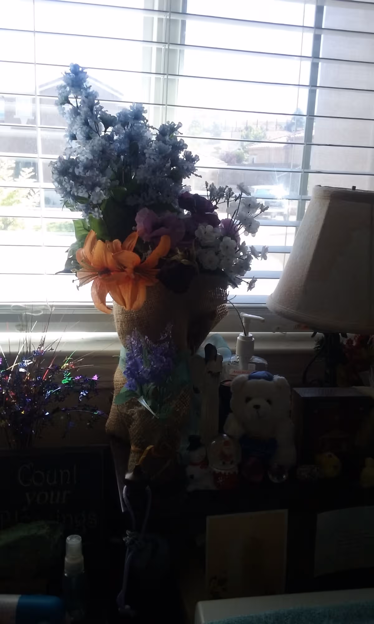 Bouquets of flowers arranged on a windowsill beside a lamp.