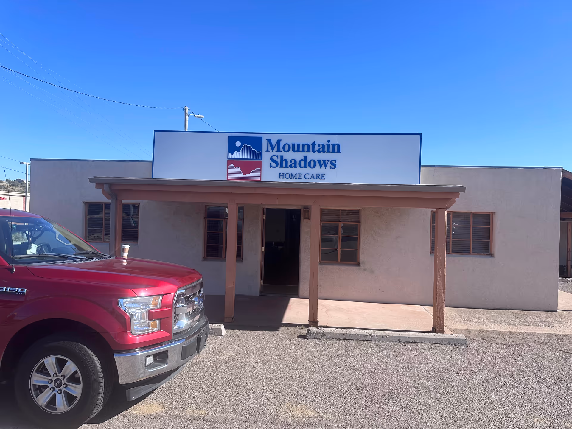 Exterior view of Mountain Shadows Home Care with a red pickup truck parked at the entrance.