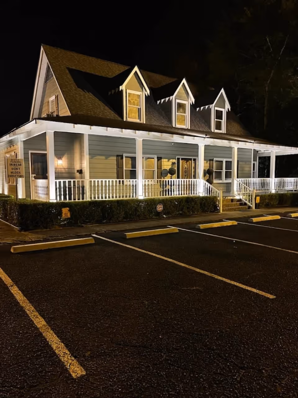 Nighttime exterior view of a house-style senior care facility with a lit porch.
