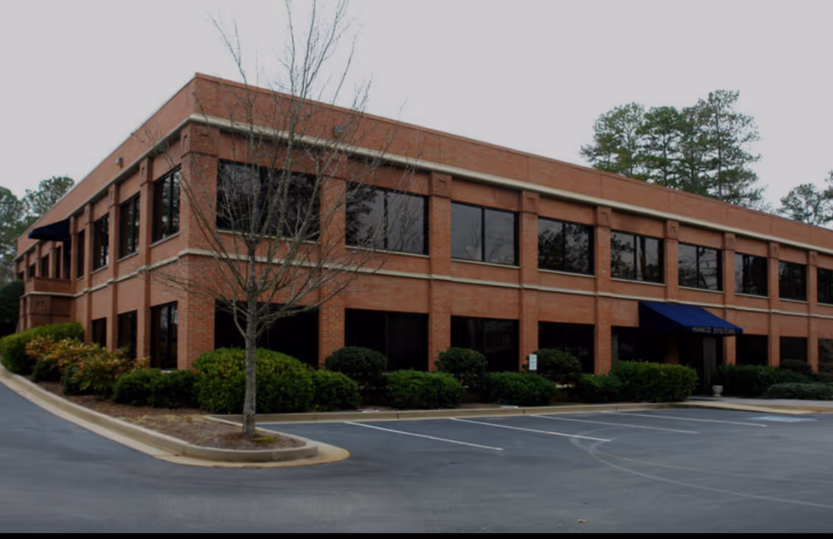 Two-story brick building exterior with large windows and a blue entrance awning.