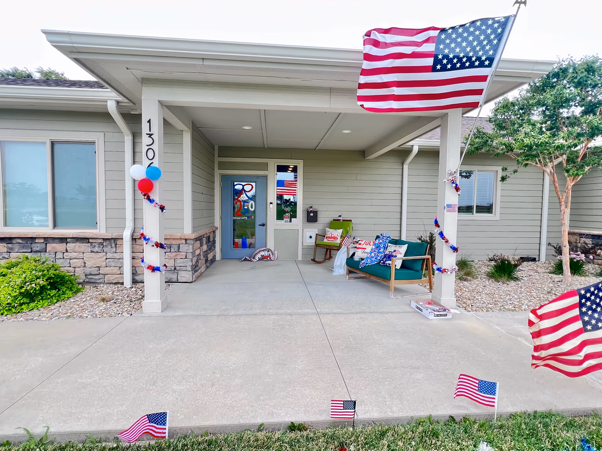 Entrance to Oakley Place of Seneca featuring patriotic decorations, flags, balloons, and outdoor seating.