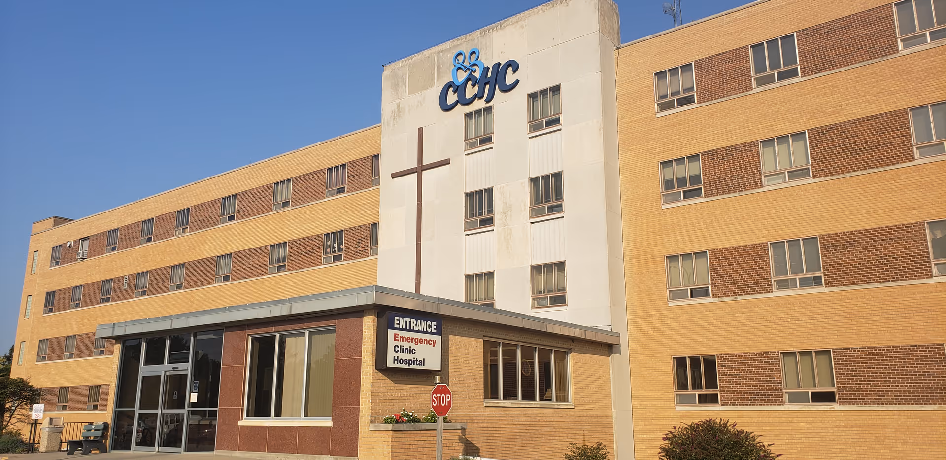 Exterior view of a multi-story hospital with a prominent entrance and cross symbol.