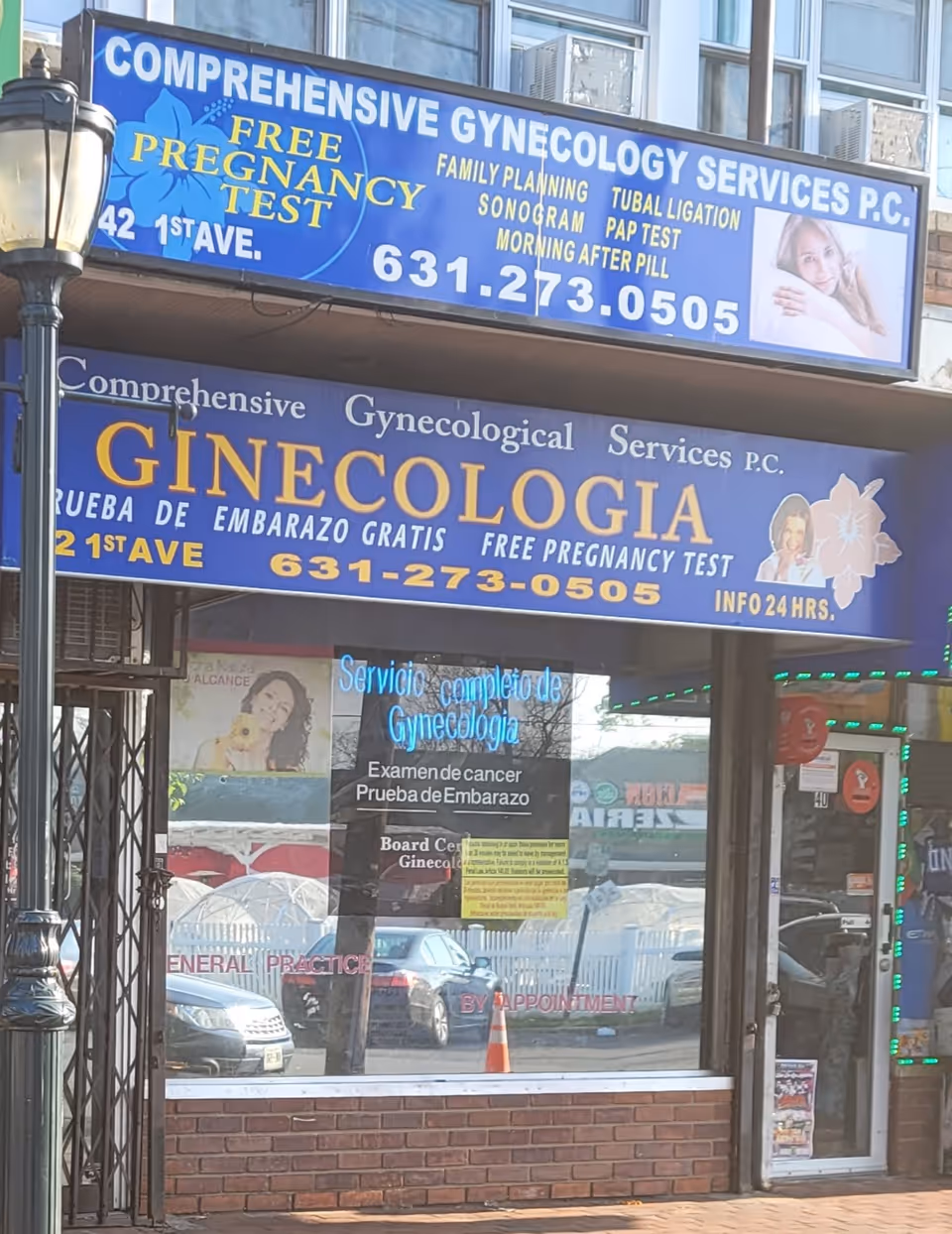 Blue signage advertising comprehensive gynecology services on storefront with windows and parked cars.