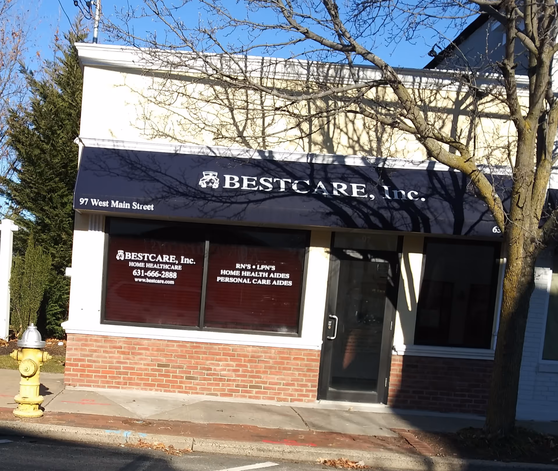 Storefront of BestCare, Inc. with a blue awning and brick facade.