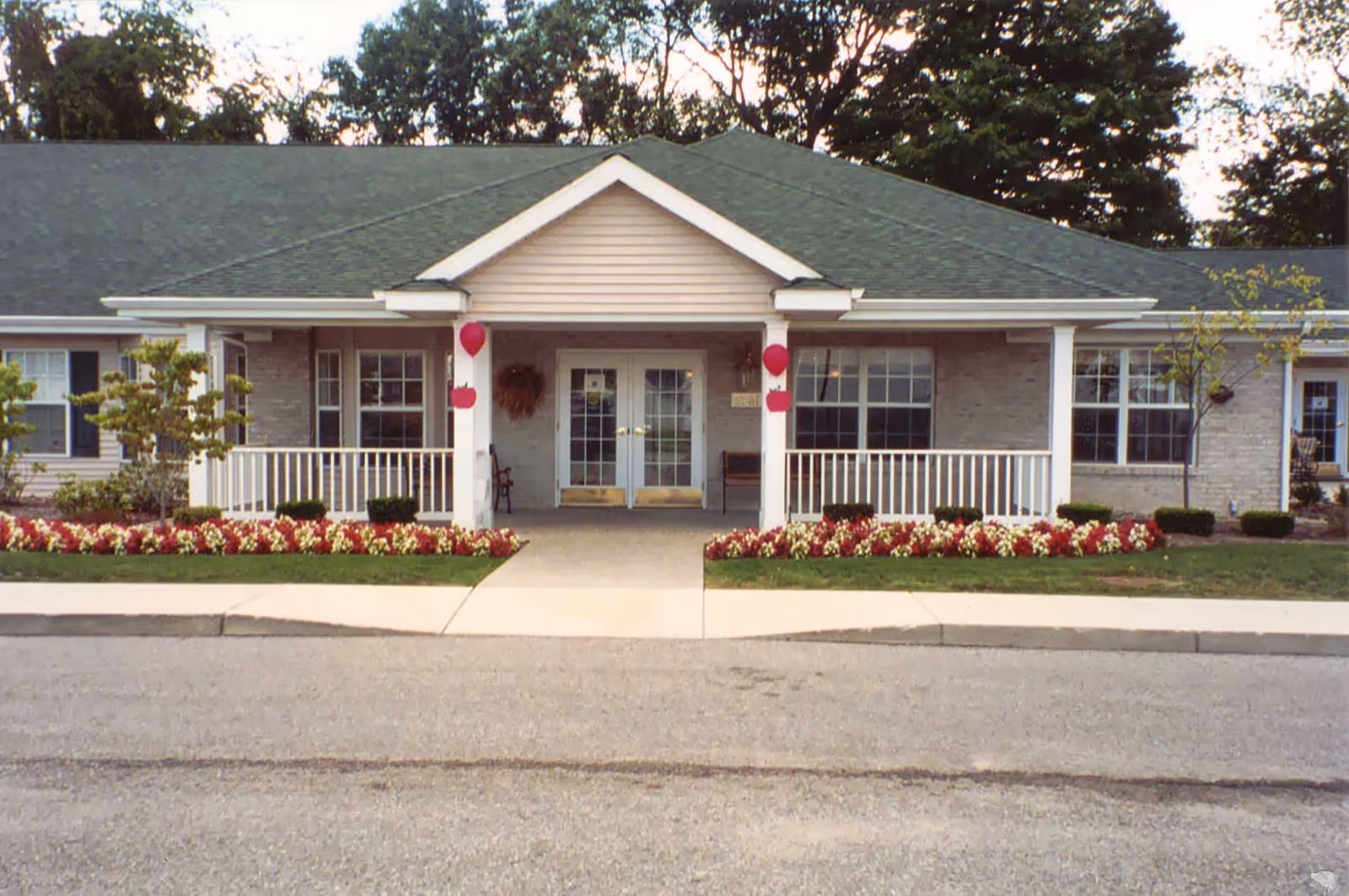 Front view of Green Acres of Greenville exterior with a flower bed and covered entrance.