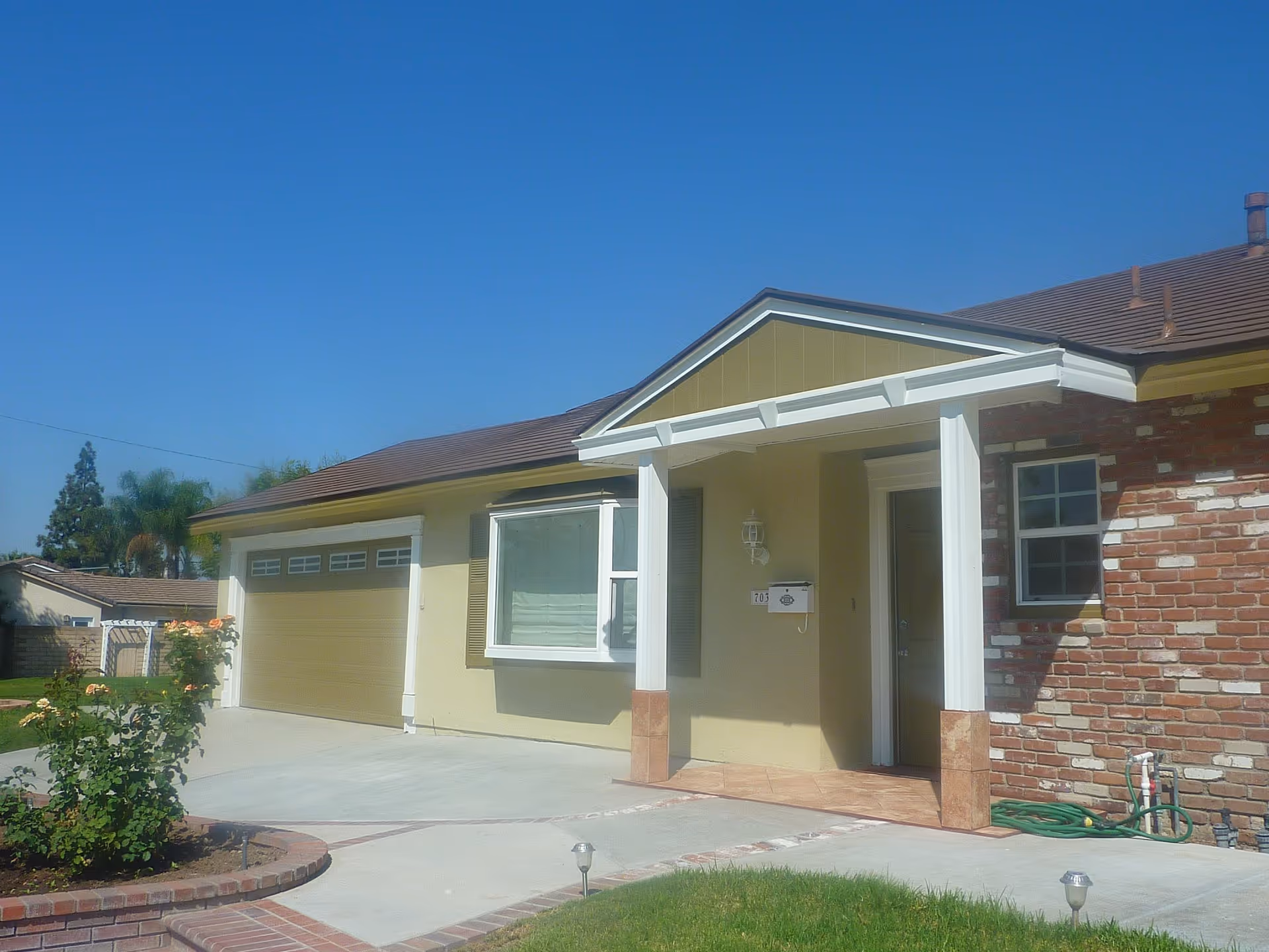 Front view of a single-story senior care residence with porch and garage.