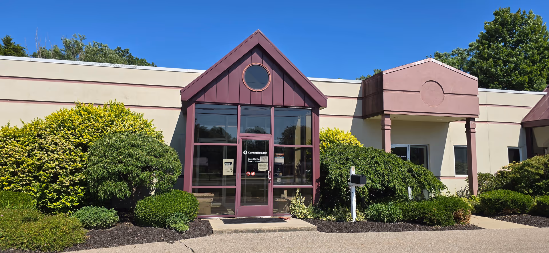 Exterior view of Corewell Health Hospice entrance with purple trim and shrubs.