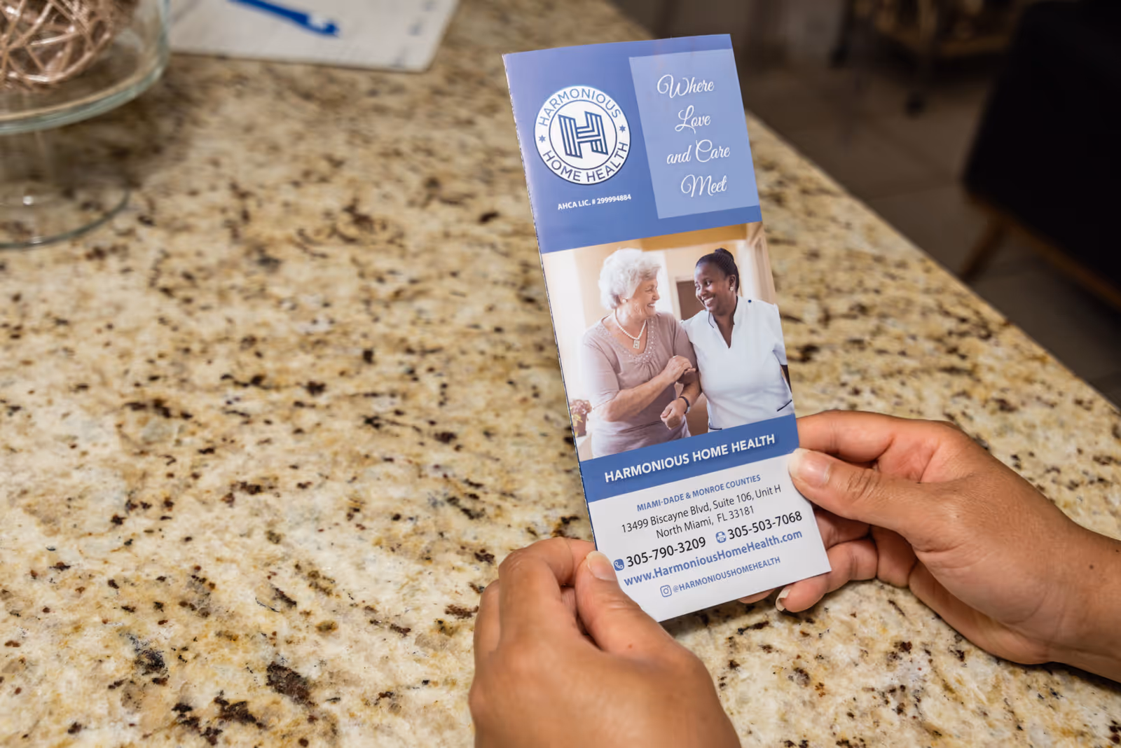 A Harmonious Home Health brochure is held on a granite kitchen counter.