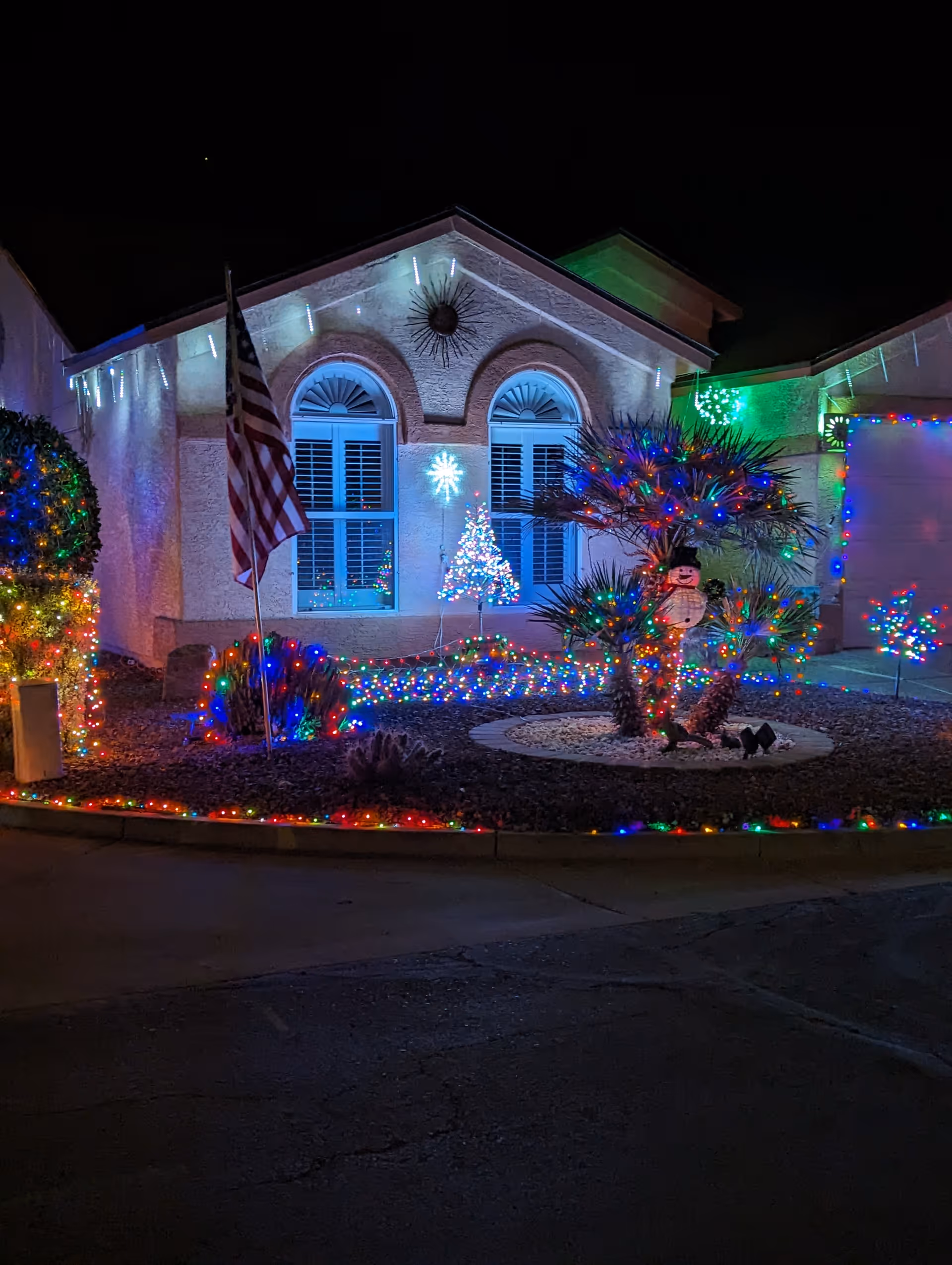 Sunbird facility front exterior festooned with Christmas lights and an American flag.