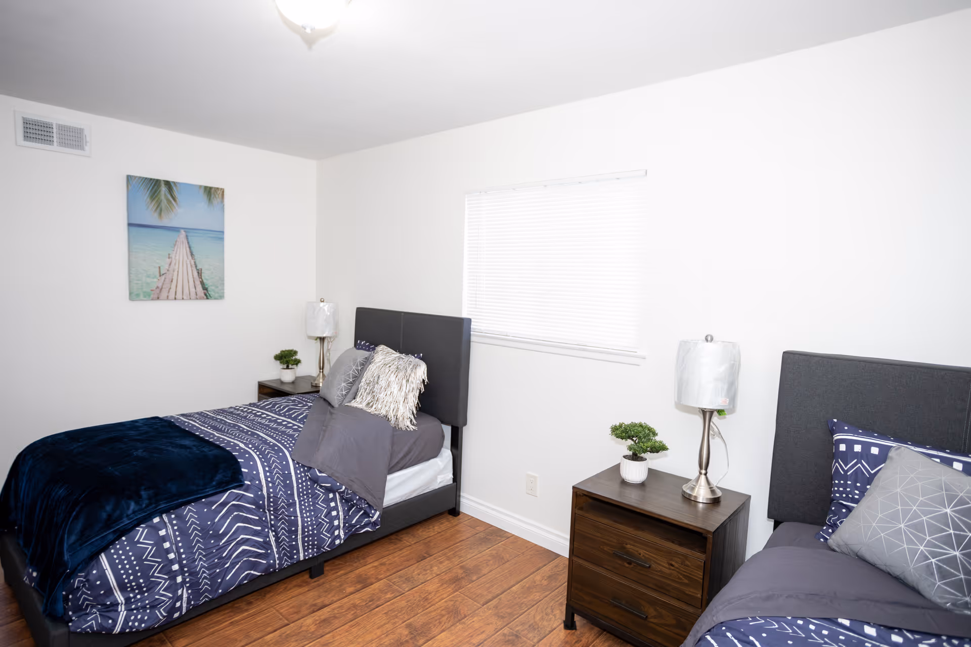 Two twin beds with nightstands and lamps in a bright, minimalist bedroom.