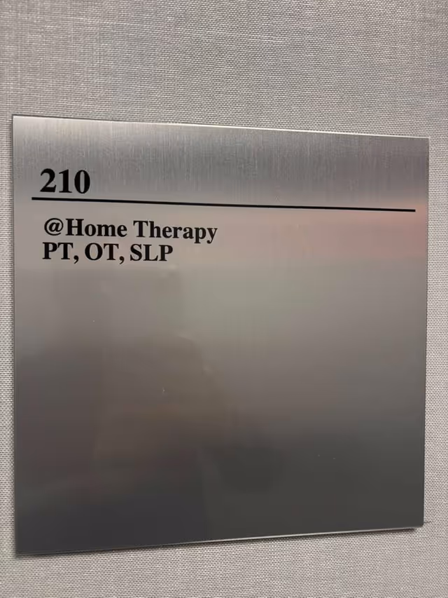 Metal room sign reads 210 and '@Home Therapy PT, OT, SLP'.