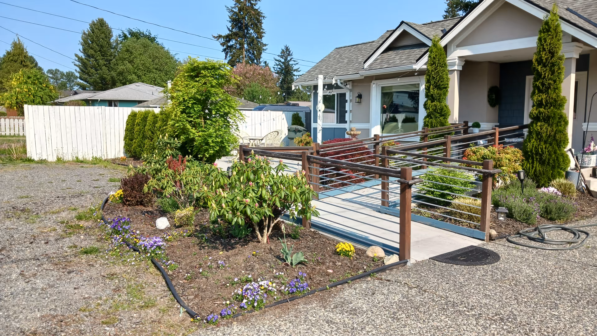 Front view of a single-story home with a wooden ramp and landscaped garden.