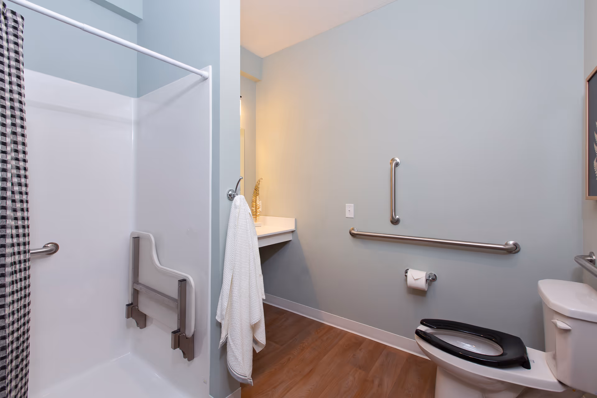 Accessible bathroom with shower, grab bars, sink, and toilet in blue walls.