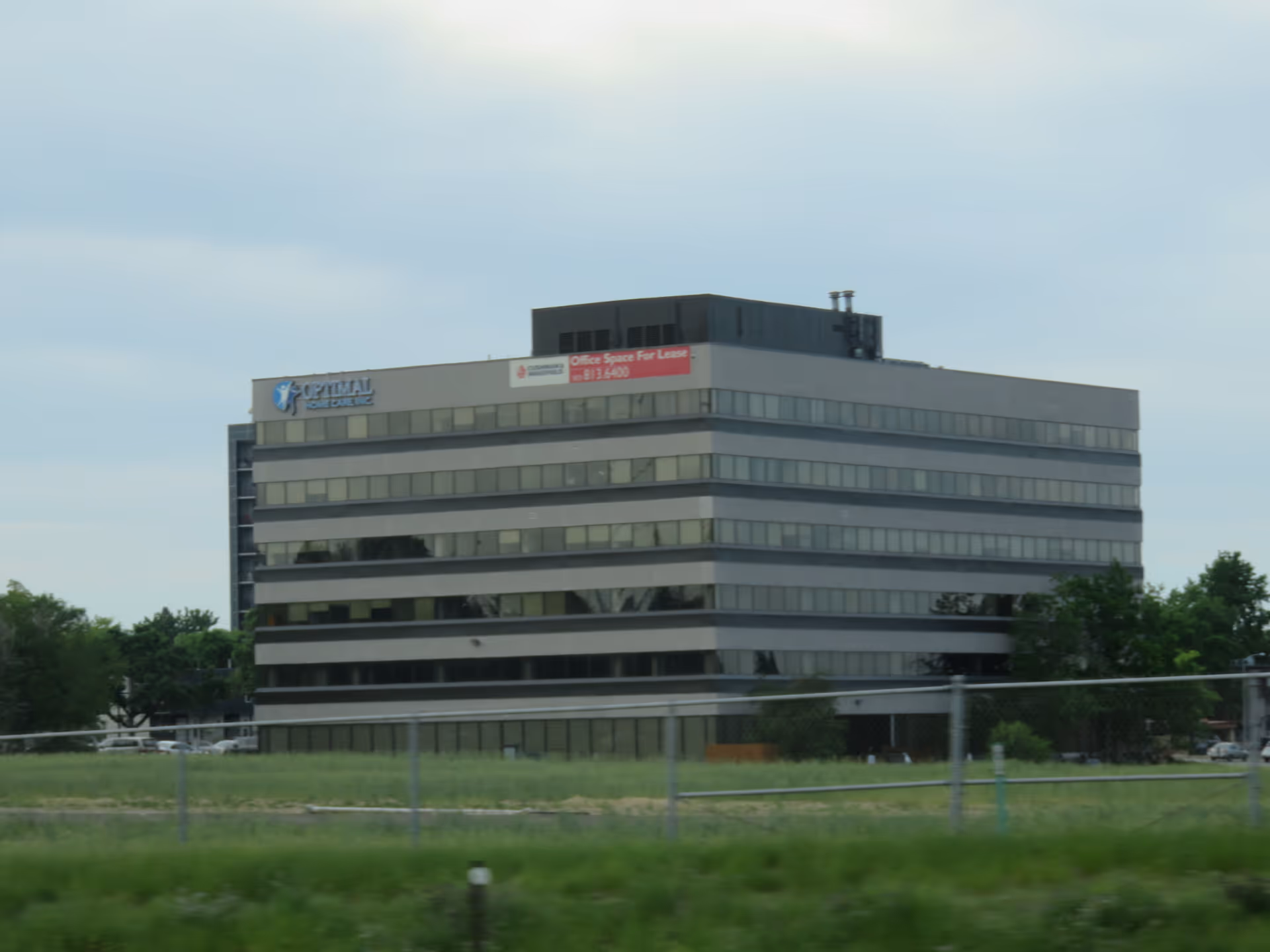 Exterior view of a multi-story building with Optimal Home Care signage and glass windows.