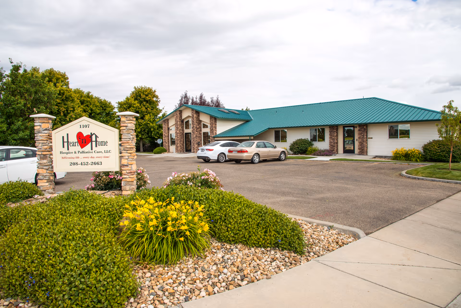 Exterior view of Heart 'n Home Hospice building with sign, parking lot, and landscaped entrance.