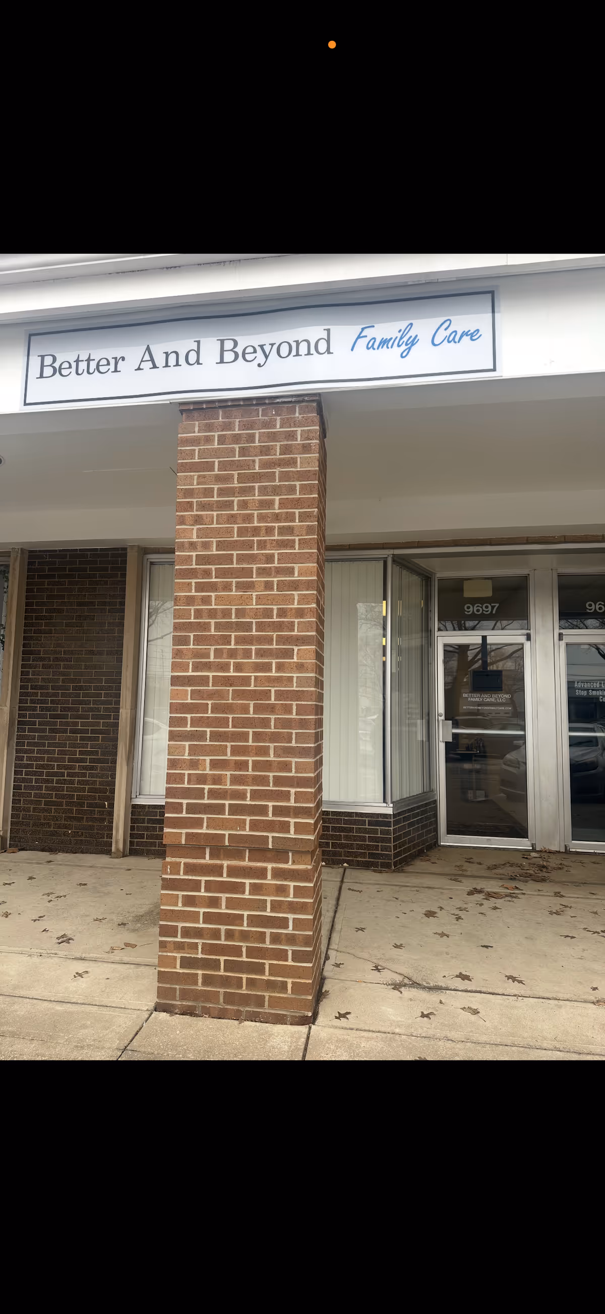 Front entrance of Better And Beyond Family Care facility with brick column and glass doors.