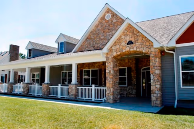 Front exterior of Dolan Memory Care at Calais with a stone-arched entrance and porch.