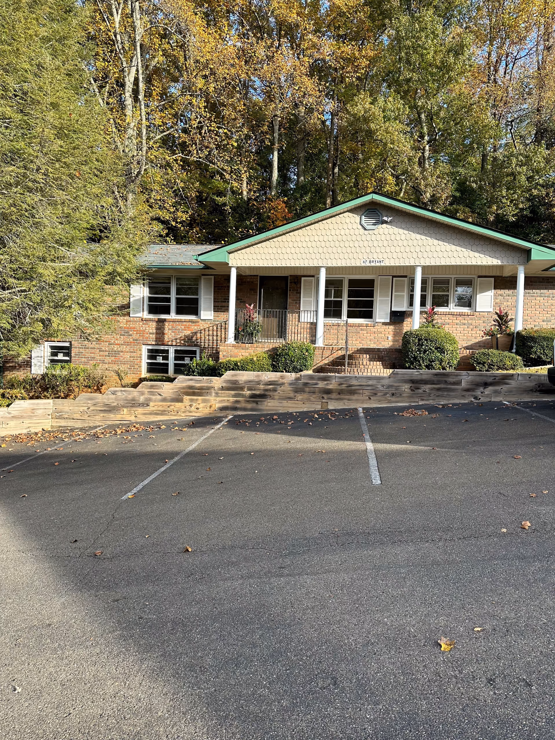 Front view of a brick senior living facility with entry steps and parking.