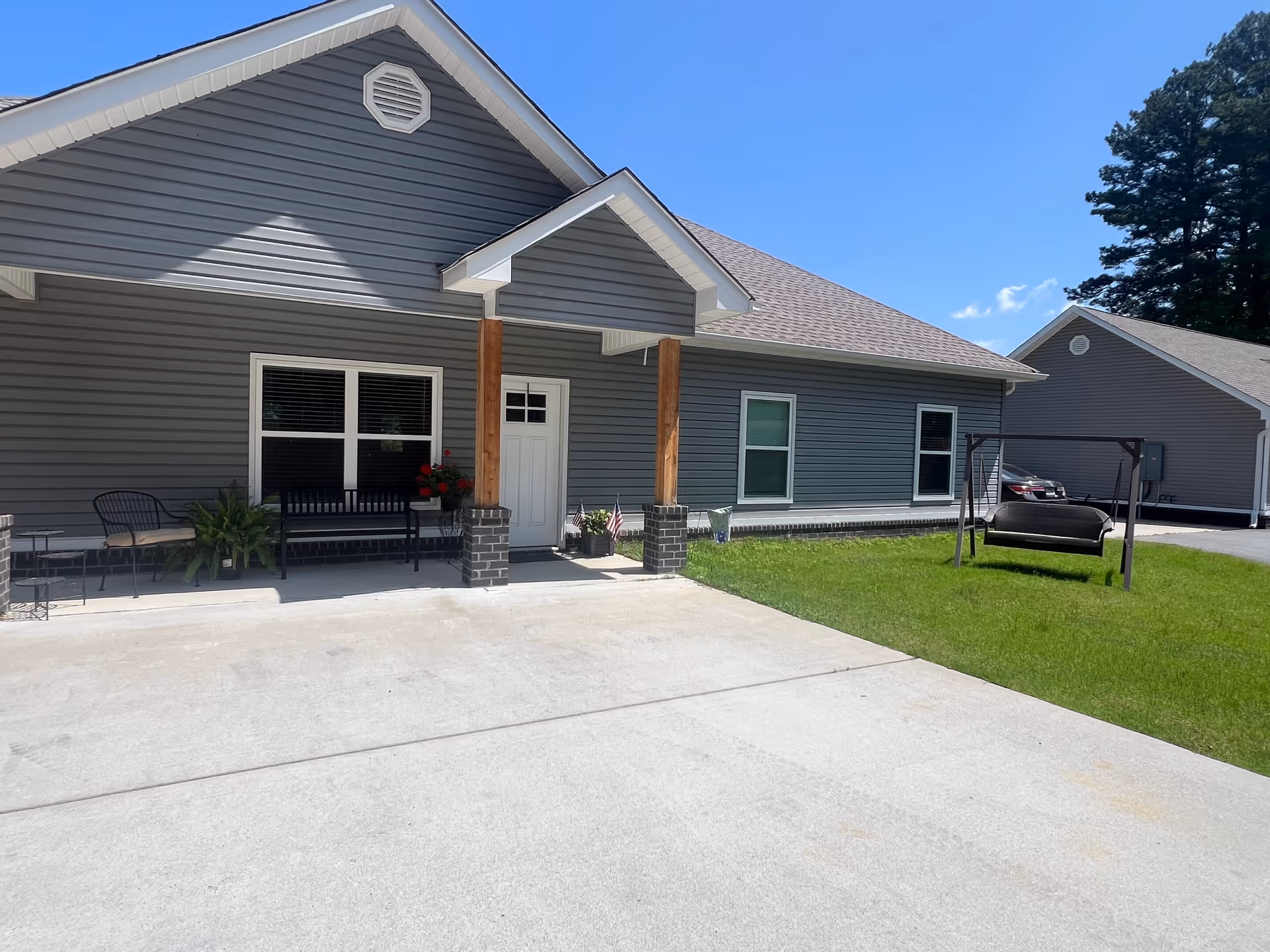 Front view of a Pleasant Hill Care Homes building with porch seating and a green lawn.