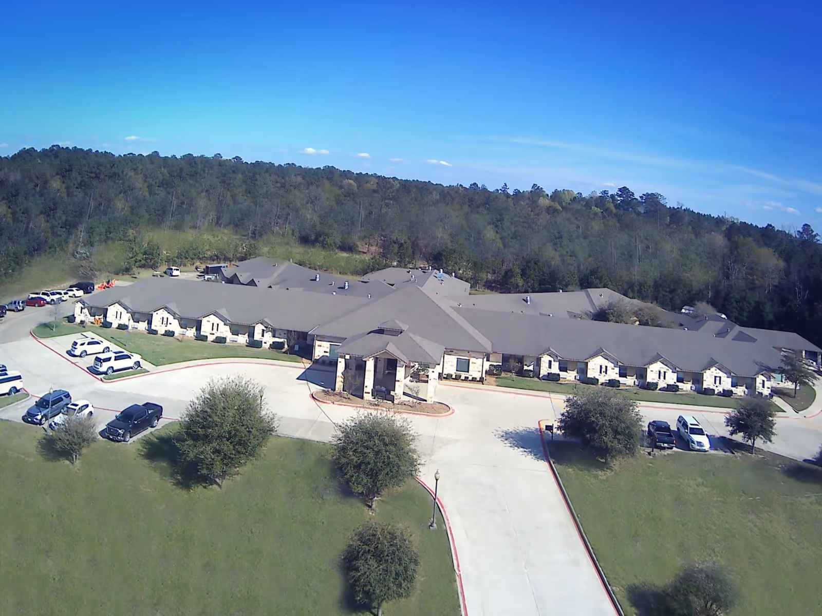 A large senior living facility with multiple wings sits on landscaped grounds.