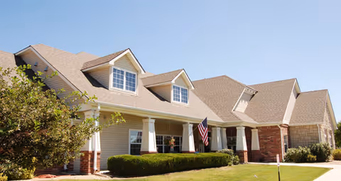 Front exterior view of Brookdale Fort Collins Assisted Living building, with lawn, shrubs, and American flag.