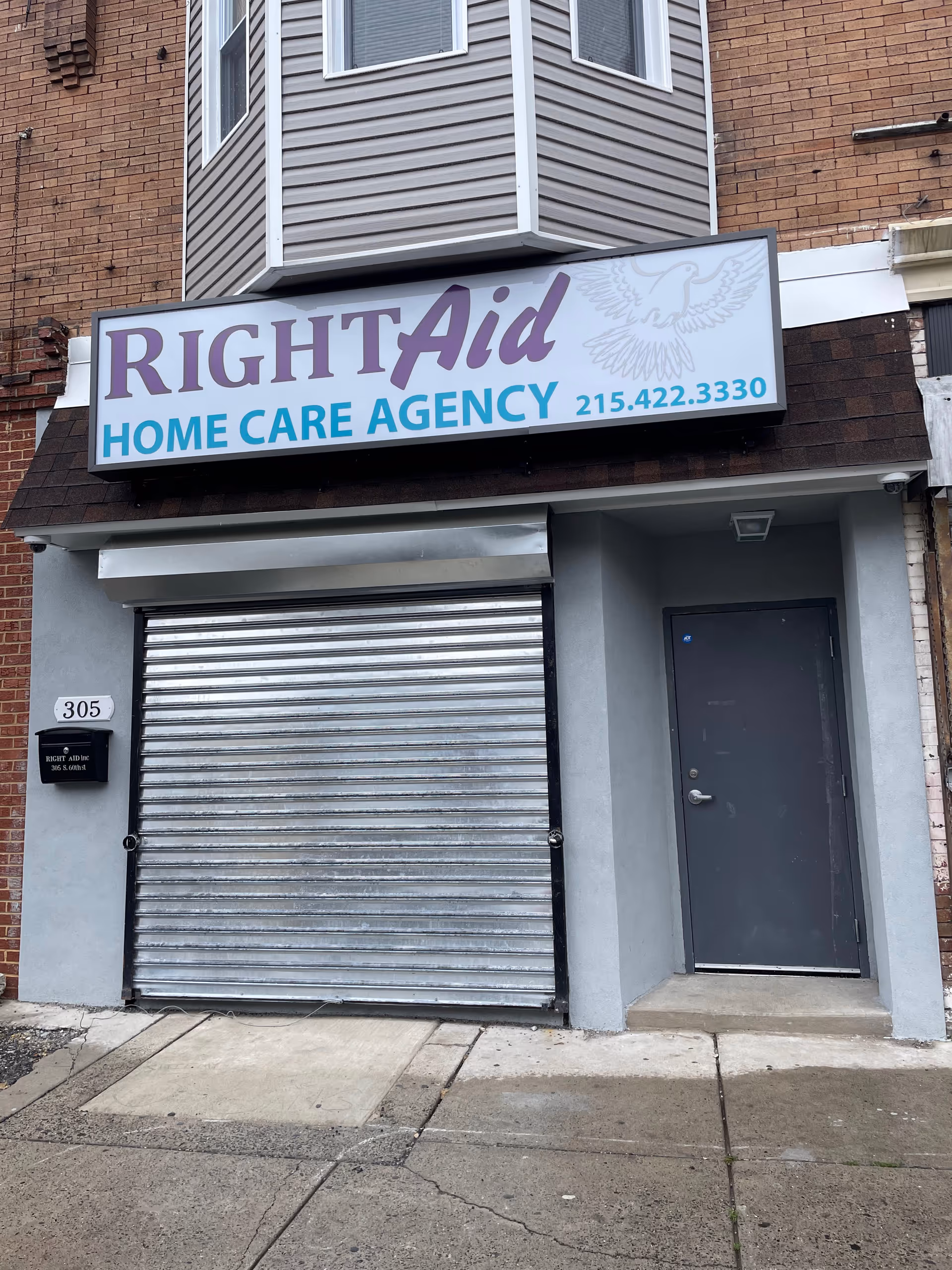 Exterior storefront with Right Aid Home Care Agency sign and metal roll-up door