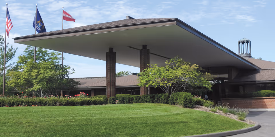 West-facing entrance to a senior living facility with a wide canopy and brick columns.