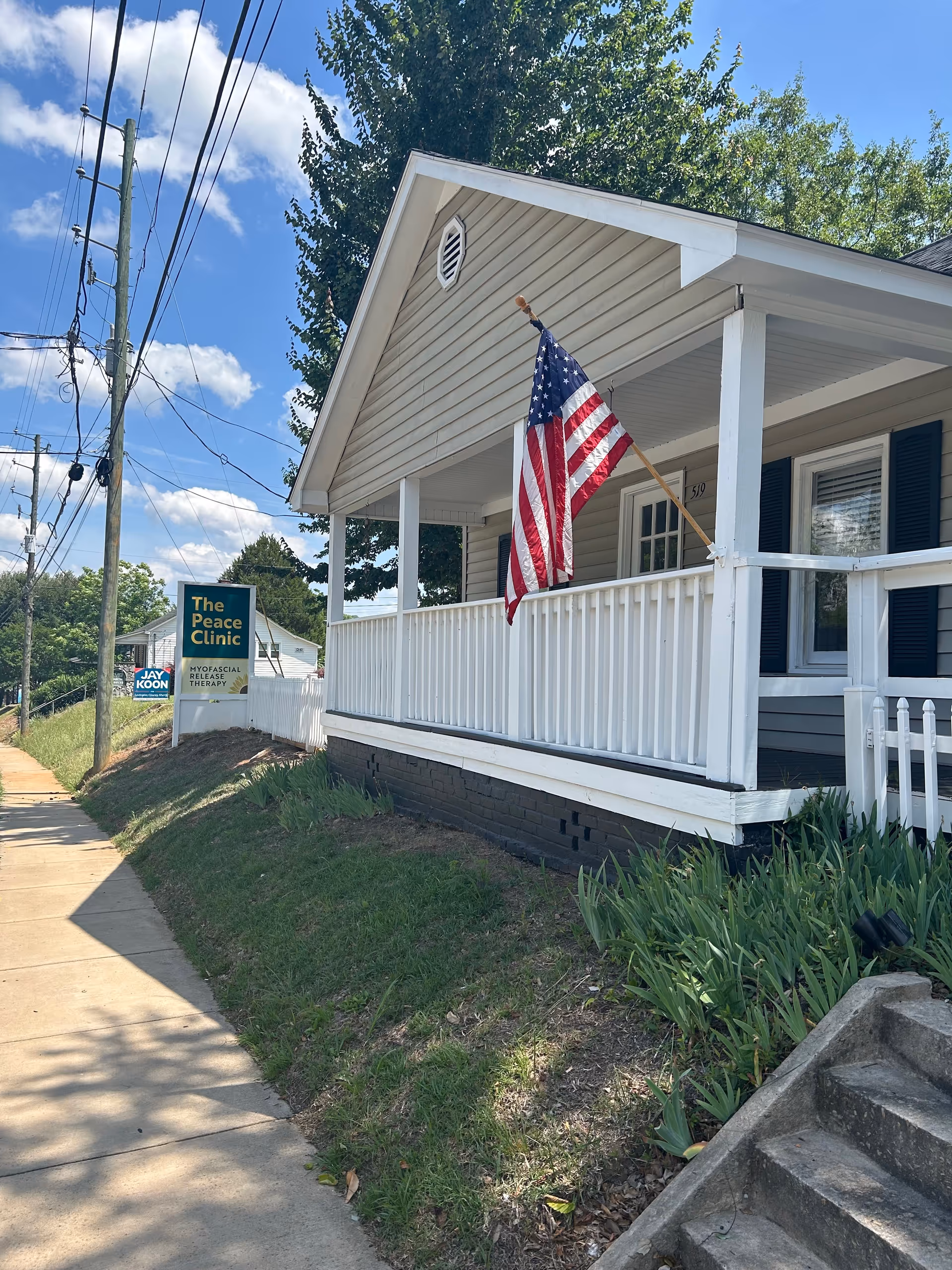 Front exterior of The Peace Clinic building with an American flag on the porch.