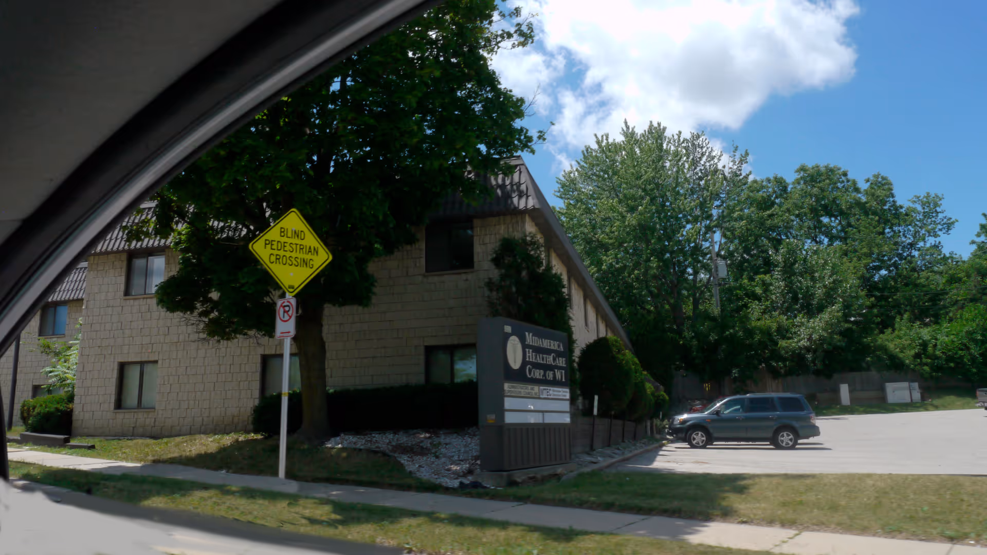 Exterior view of a Mid America Healthcare building with sign and parked car.