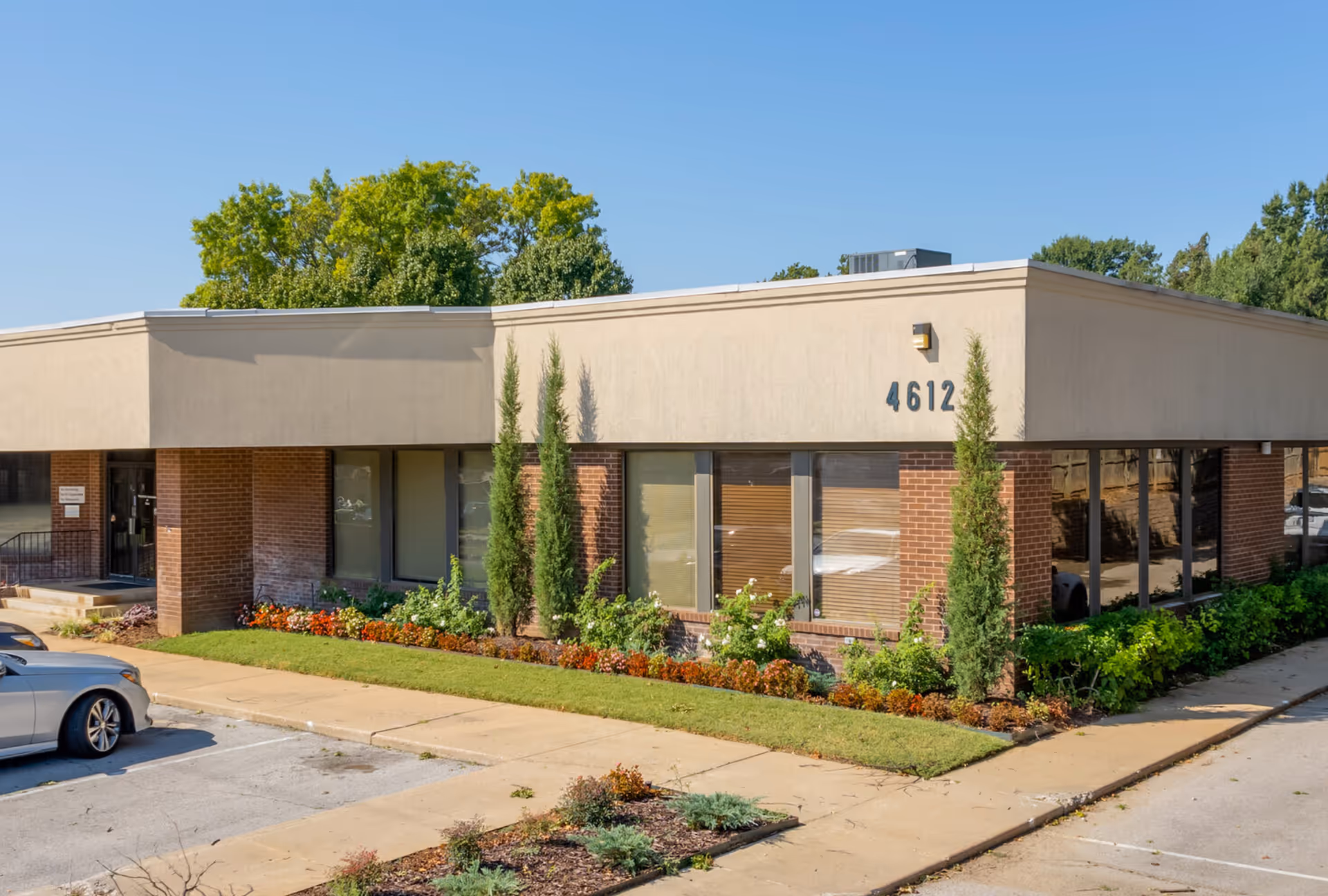 Single-story beige building with large windows and manicured landscaping.